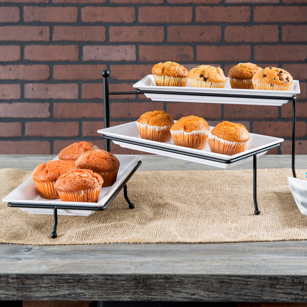 An American Metalcraft three-tier rectangular display stand with trays of muffins on a table.