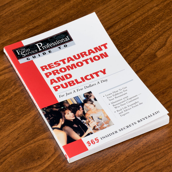 A book titled "Restaurant Promotion and Publicity" on a table in a fine dining restaurant.