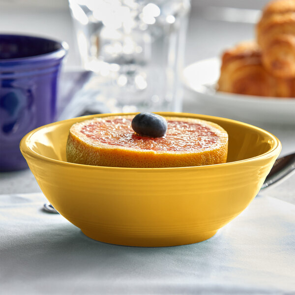 A grapefruit and blueberry in a yellow Tuxton nappie bowl.