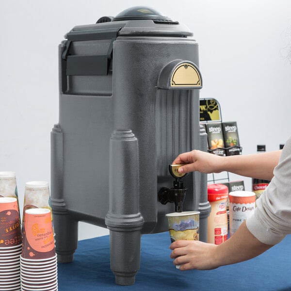 A woman using a Cambro insulated beverage dispenser to pour coffee.