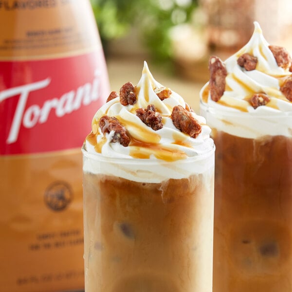 A glass of iced coffee with whipped cream, caramel sauce, and nuts.