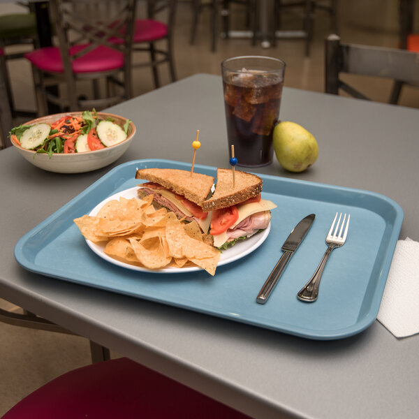 A Carlisle blue plastic fast food tray with a sandwich and chips on it.