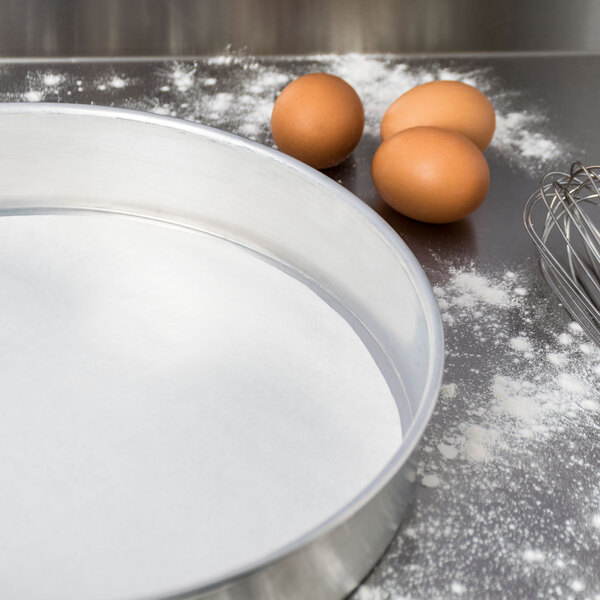 A metal pan lined with Baker's Mark parchment paper next to brown eggs.