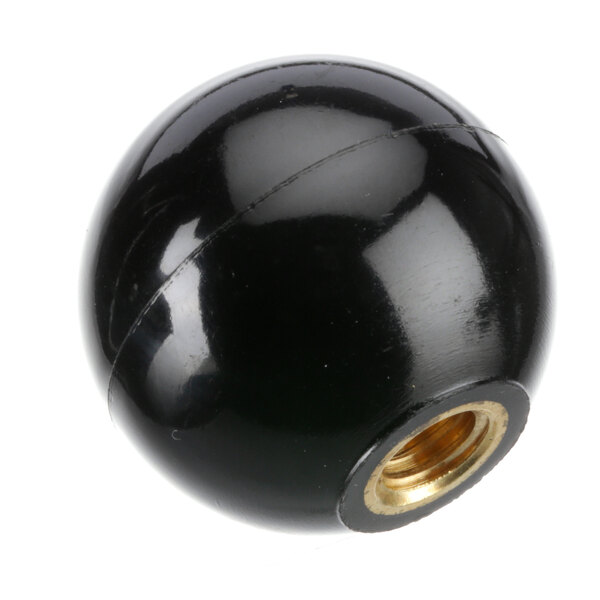 A close-up of a black round knob with a gold nut.
