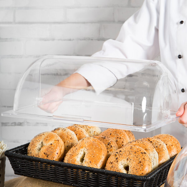 A person using a GET Designer Polyweave clear rectangular cover to display a tray of bagels.