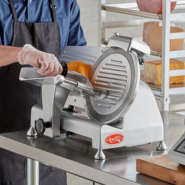 A man using an Avantco meat slicer to slice cheese on a counter.