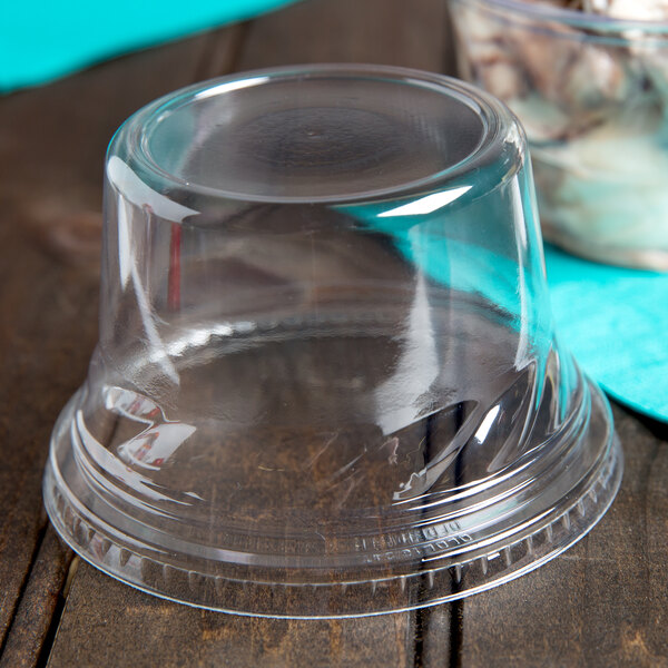 A clear Fabri-Kal plastic dome lid on a wood surface.