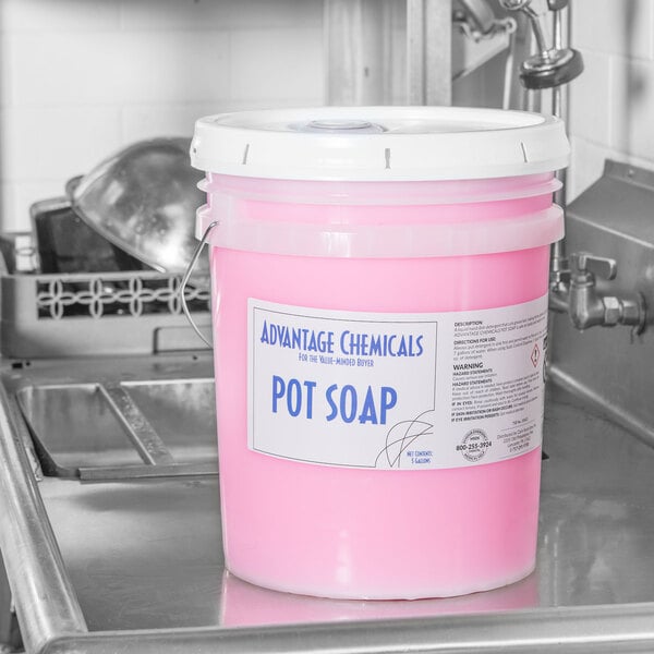A pink bucket of Advantage Chemicals concentrated pot & pan soap on a counter.