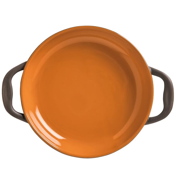 An orange stoneware round baker with two handles.