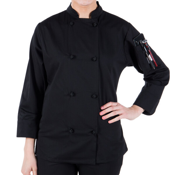 A woman wearing a Mercer Culinary Millennia black long sleeve chef jacket.