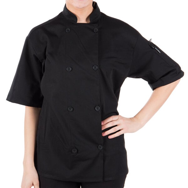 A woman wearing a Mercer Culinary black chef coat with a mesh back.