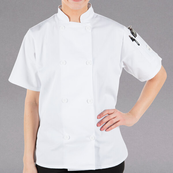 A woman wearing a Mercer Culinary white short sleeve chef jacket.