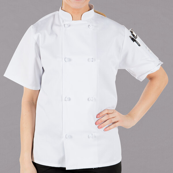 A woman wearing a Mercer Culinary white chef's coat with cloth knot buttons.