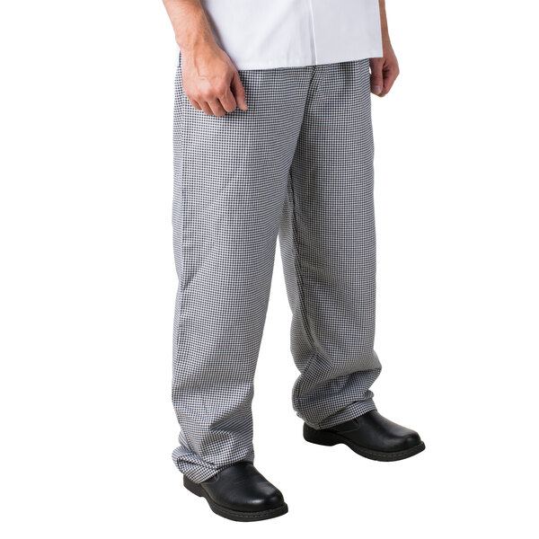 A person wearing Mercer Culinary houndstooth chef pants and black shoes.