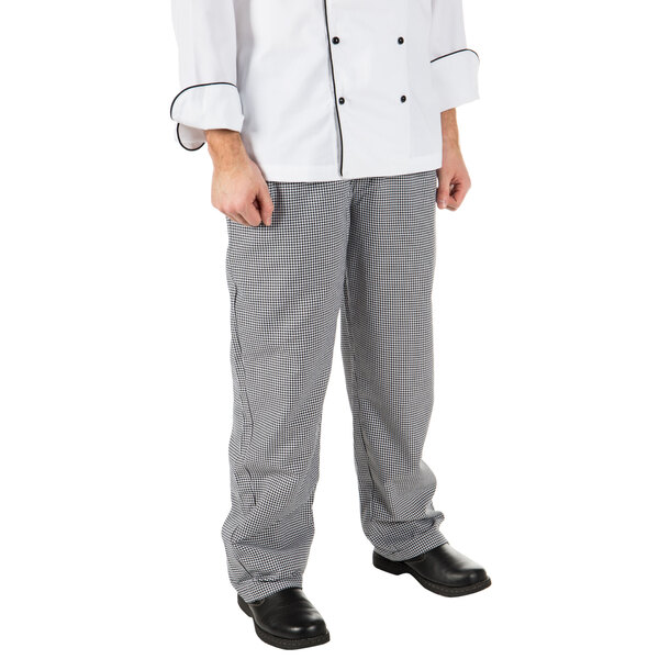 A person wearing Mercer Culinary Millennia Houndstooth chef pants and a white chef coat.