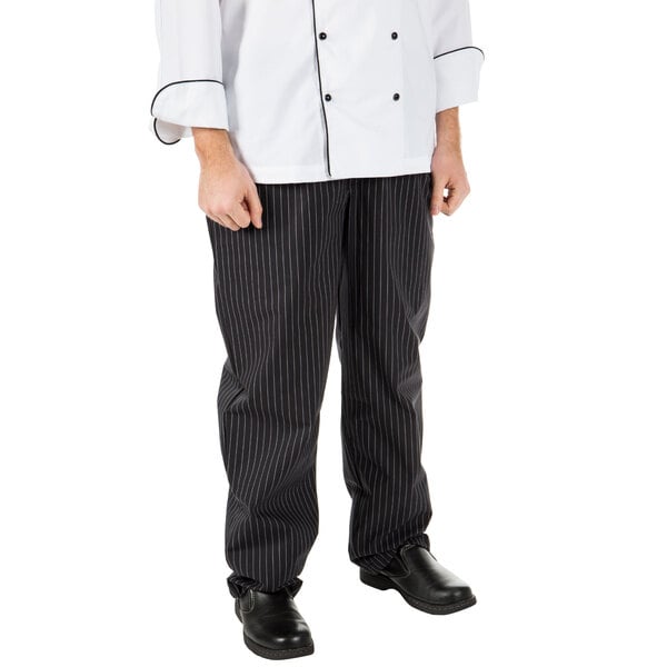 A person wearing Mercer Culinary black pinstripe chef pants in a professional kitchen.