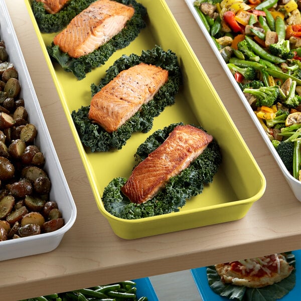 A yellow Cambro tray of food with salmon and vegetables.