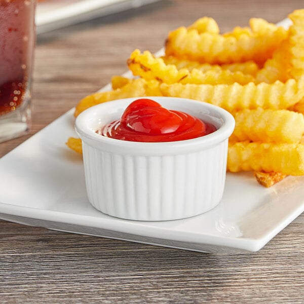 A plate of french fries with a bowl of ketchup on the side.