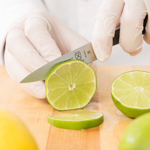A person using a Mercer Culinary Z&#252;M&#174; forged paring knife to cut a lime.