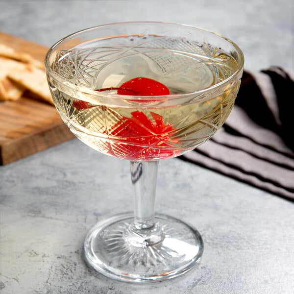 A Libbey coupe cocktail glass filled with liquid and a cherry.