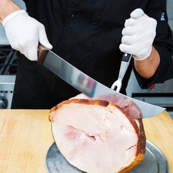 A person using a Victorinox Cimeter Knife to cut ham.