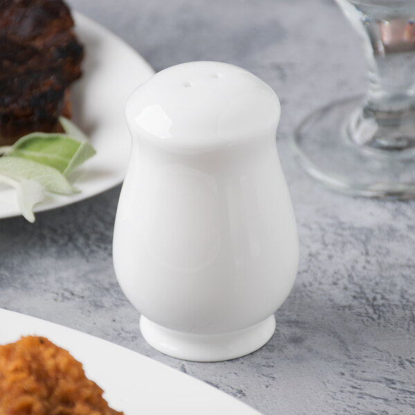 A Reserve by Libbey bone china salt shaker on a table with food.