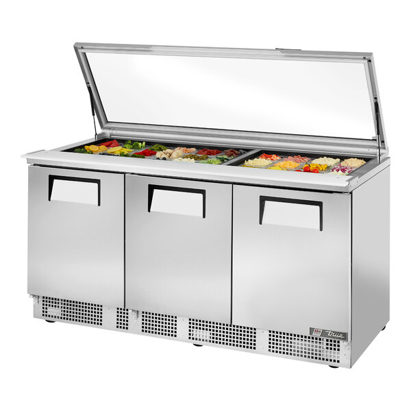 A True refrigerated sandwich prep table with a hinged glass lid on a counter.