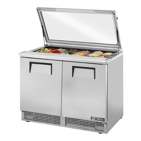 A True refrigerated sandwich prep table with a hinged glass lid on a counter.