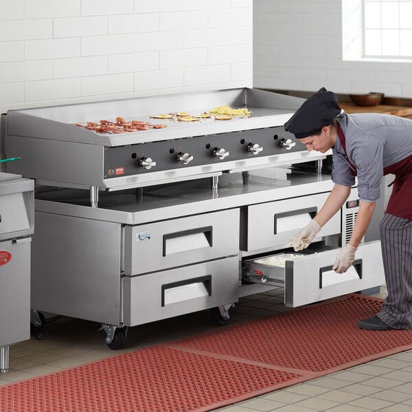 A chef using an Avantco 72" refrigerated chef base to store food.