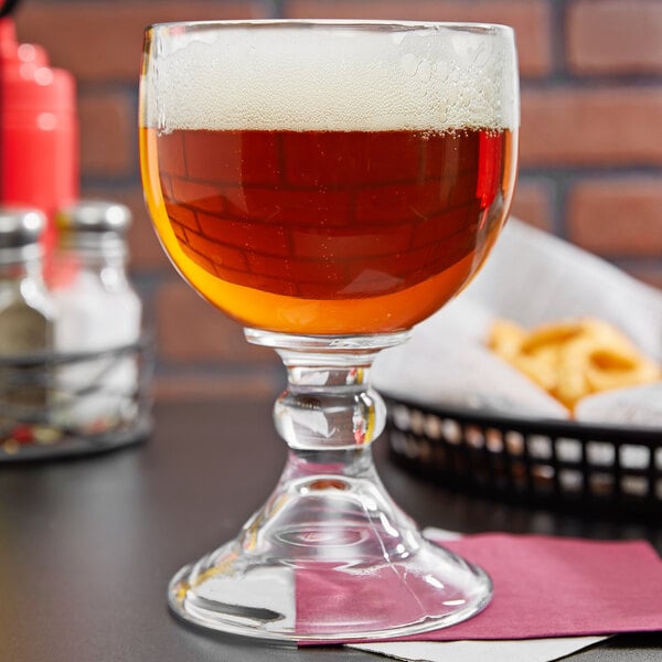 A Libbey Schooner glass of beer sits on a table.