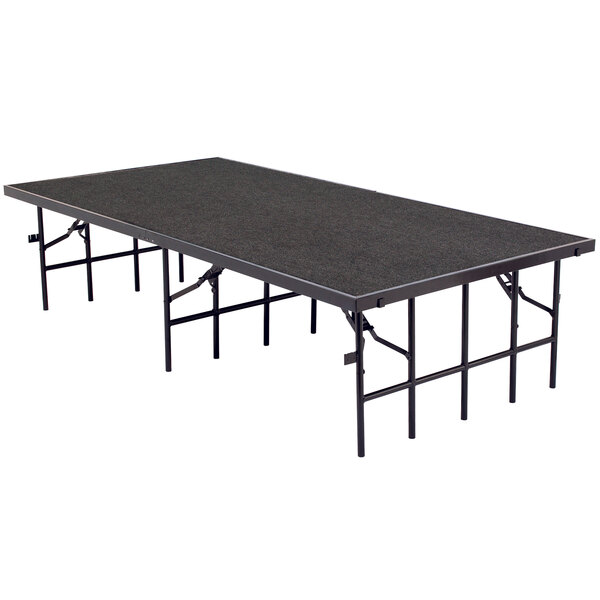 A National Public Seating single height portable stage with gray carpet on a black rectangular table with legs.
