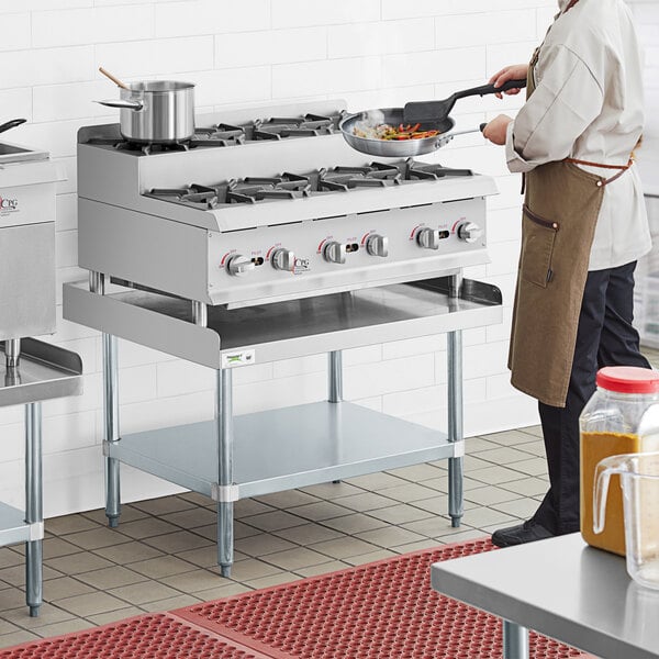 A man cooking food on a Cooking Performance Group countertop range with 6 burners.