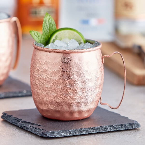 A copper mug with ice and lime on a stone coaster.