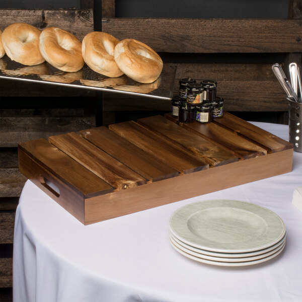 A Tablecraft Gastronorm acacia wood crate with bagels on a table.