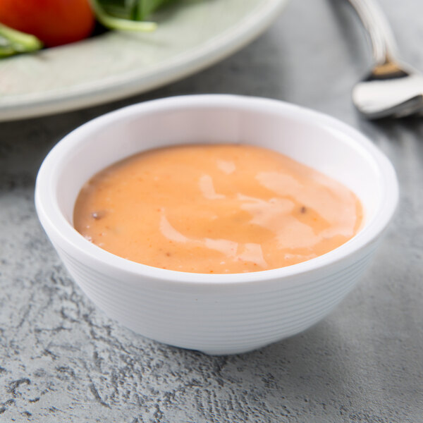 A white Tablecraft ramekin filled with sauce on a plate of food.