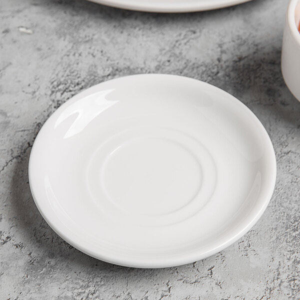 A Libbey bright white porcelain saucer on a table.