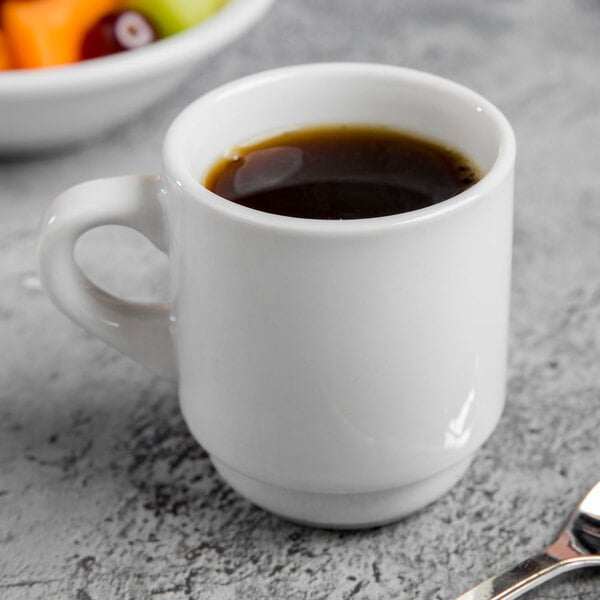 A Libbey tall porcelain espresso cup filled with coffee on a table.