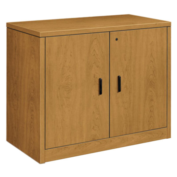 A HON laminate wood storage cabinet with two doors and black handles.