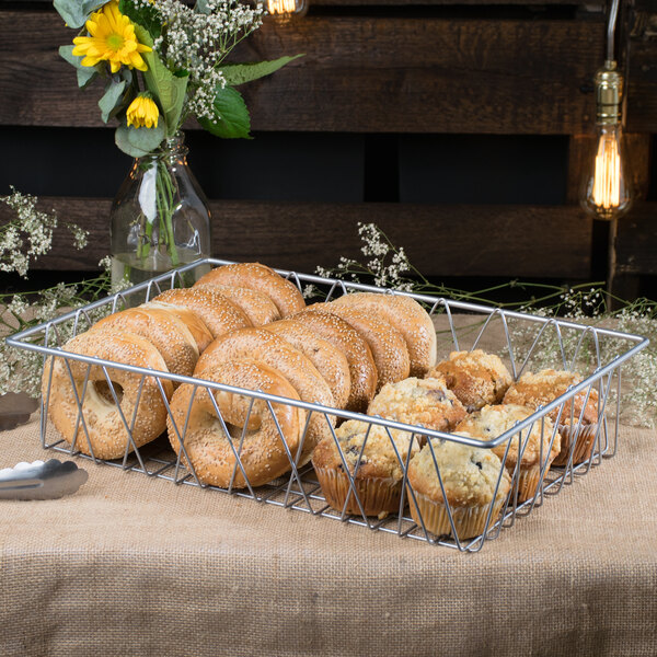 A Clipper Mill gray iron wire pastry basket filled with muffins and bagels.