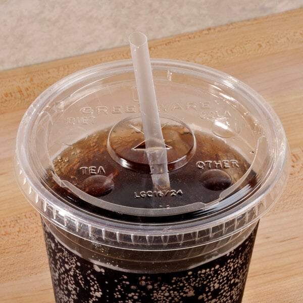 A Fabri-Kal Greenware clear plastic lid with a straw slot on a plastic cup with a straw and a brown liquid.