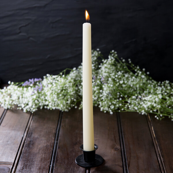 A Hyoola ivory taper candle burning on a table.
