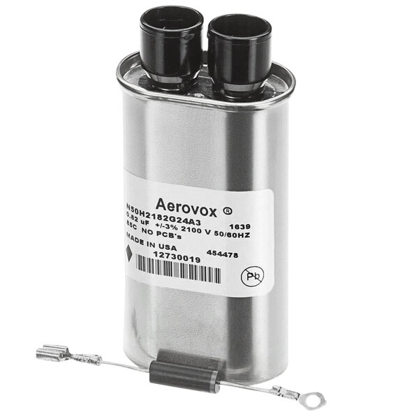 An Amana capacitor, a silver cylinder with black caps and two wires attached.