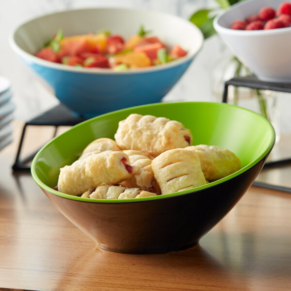 A GET Brasilia melamine bowl filled with pastries and raspberries on a table.