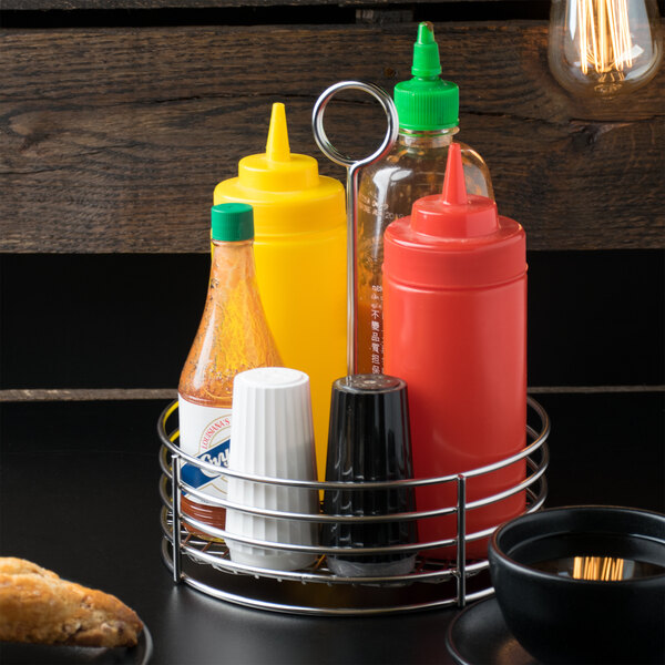 A Clipper Mill stainless steel round condiment caddy with condiments and a coffee cup inside.