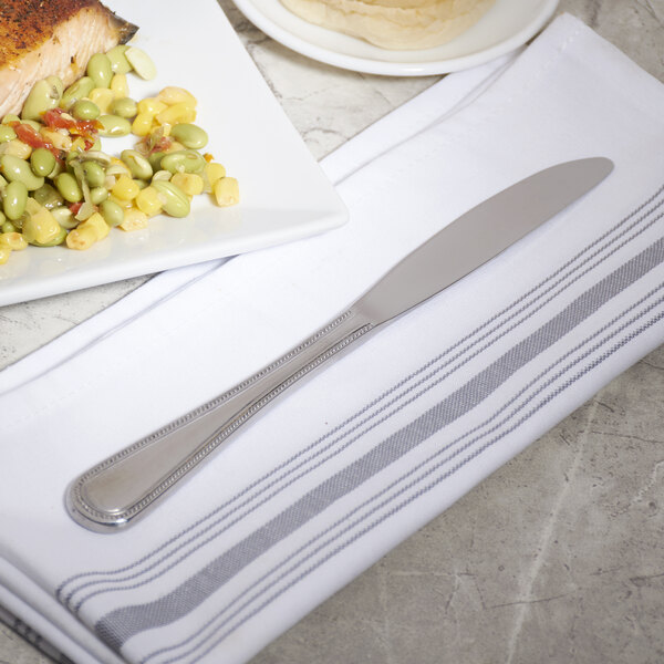 A 10 Strawberry Street stainless steel dinner knife on a plate of food.