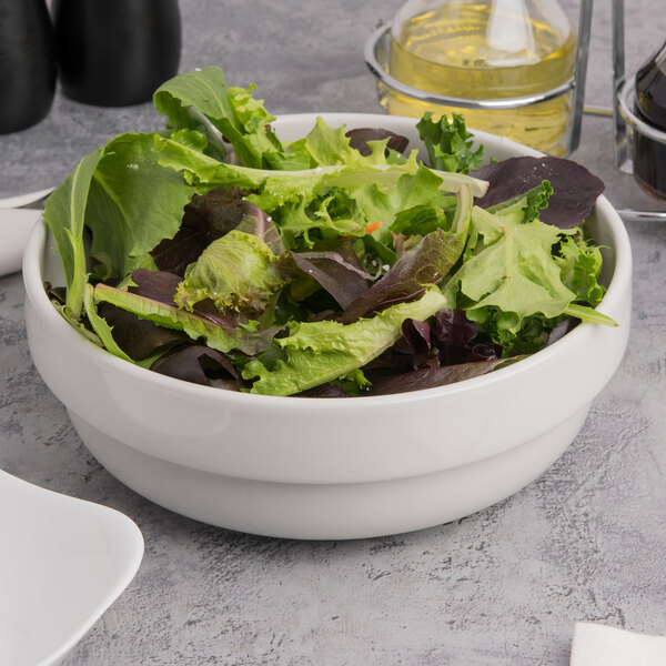 A Tuxton porcelain white china salad bowl filled with lettuce and other vegetables.
