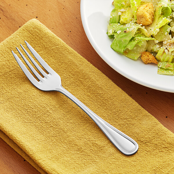 An Acopa Edgewood stainless steel salad fork on a plate of salad