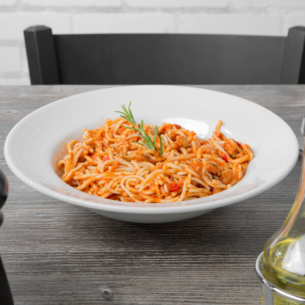 A Tuxton Pacifica bright white china pasta bowl filled with spaghetti on a table.