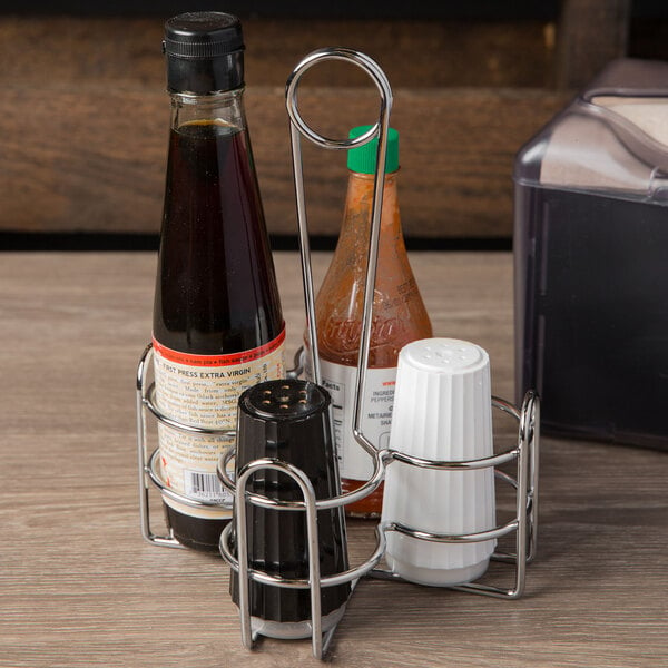 A Clipper Mill chrome metal 4-compartment condiment caddy on a table with condiments.
