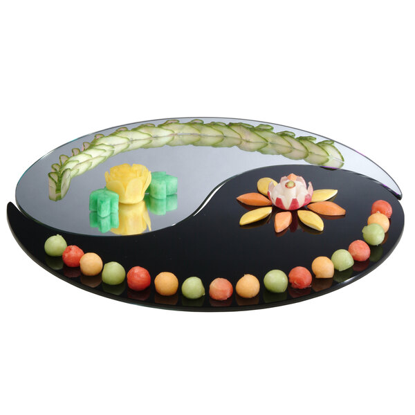 A Yin Yang shaped mirror tray with a variety of fruit on it.